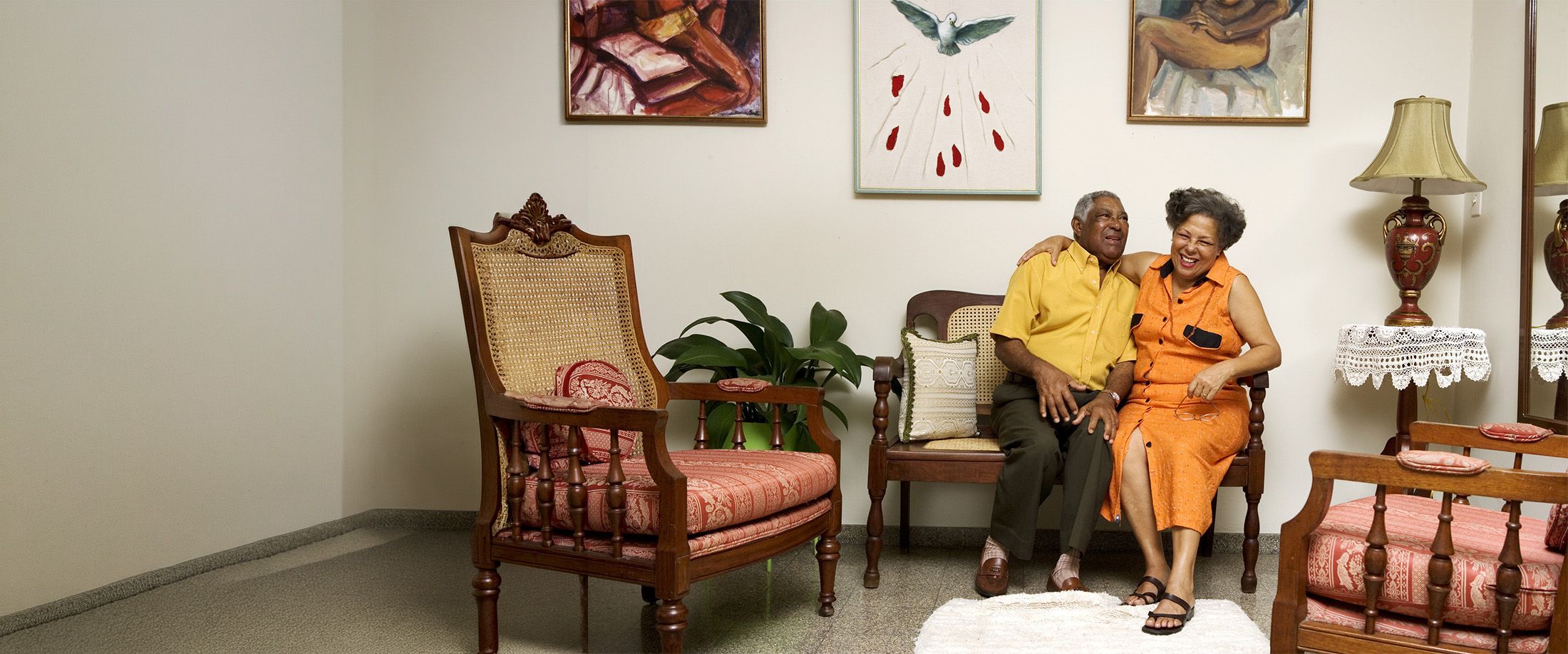 An older couple laughing together on a bench at home