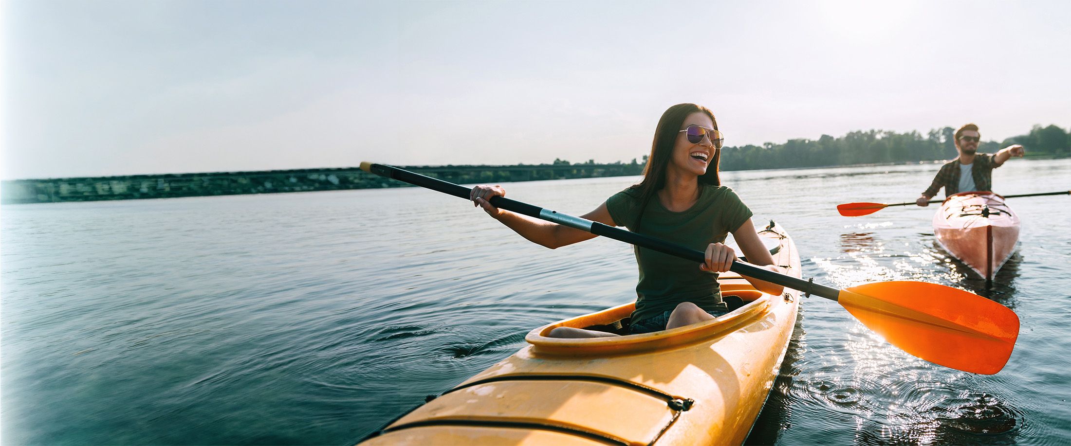 Two friends kayaking on a lake on a sunny day