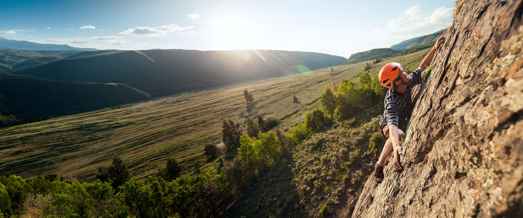 A climber in a helmet scaling a rock face
