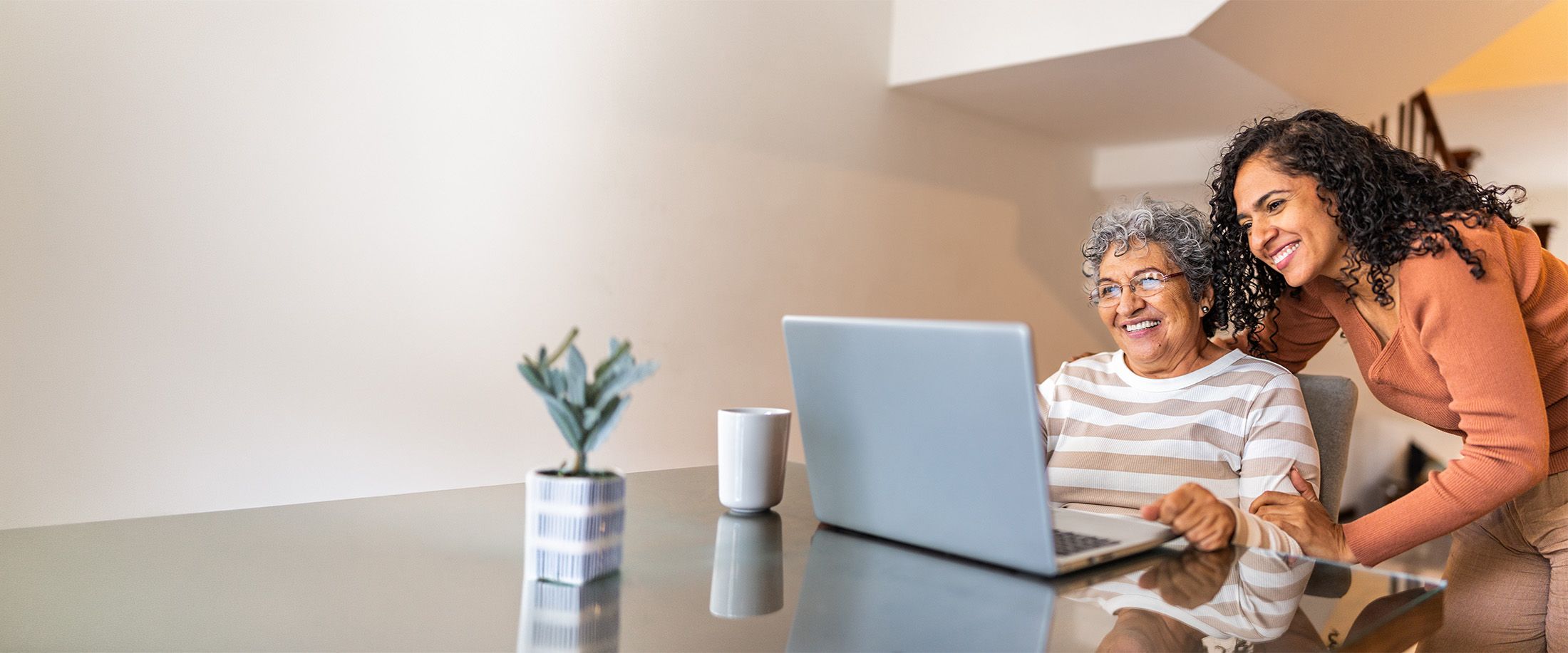 A woman and her adult daughter looking at a laptop together