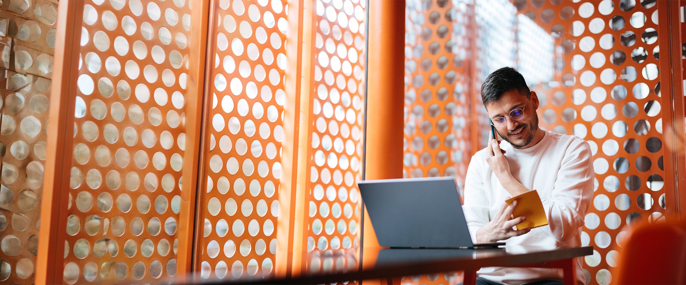 A man on the phone taking notes at his laptop