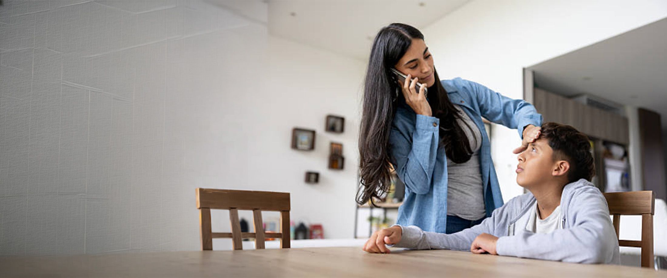A mother on the phone checking her son for a fever